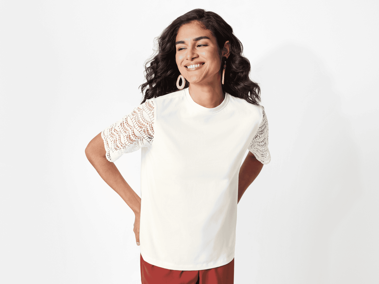 Ein Model trägt ein weißes T-Shirt mit Spitzenärmeln.
