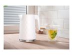 White electric kettle with a textured pattern next to a cup of hot mint tea