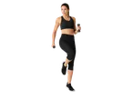 Woman exercising with dumbbells in black workout clothes.