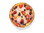 A round Dutch baby pancake topped with strawberries, blueberries, and powdered sugar.
