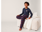 Dečak u pepperts!® pidžami sa natpisom „LAZY DAY PJ“ sedi na bež sofi.
