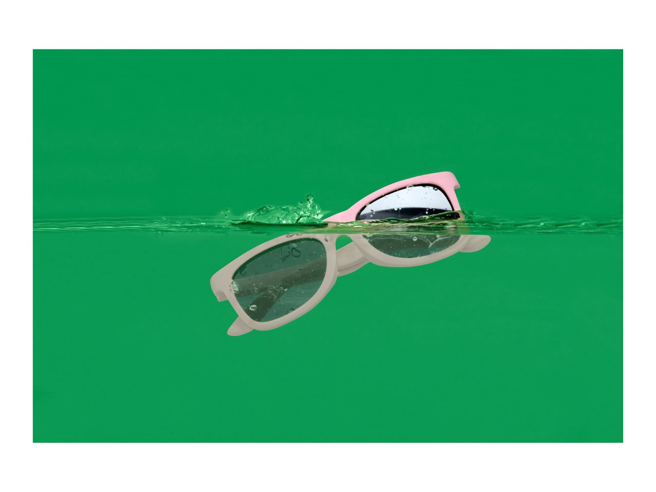 Pink and white sunglasses floating in green water with splashes.
