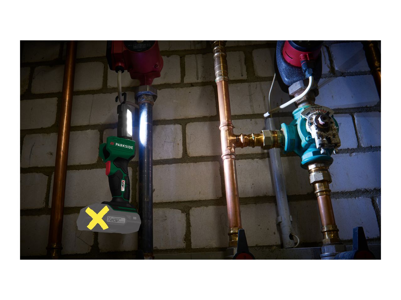 A Parkside work light illuminates pipes and a Vaillant pump in a basement.