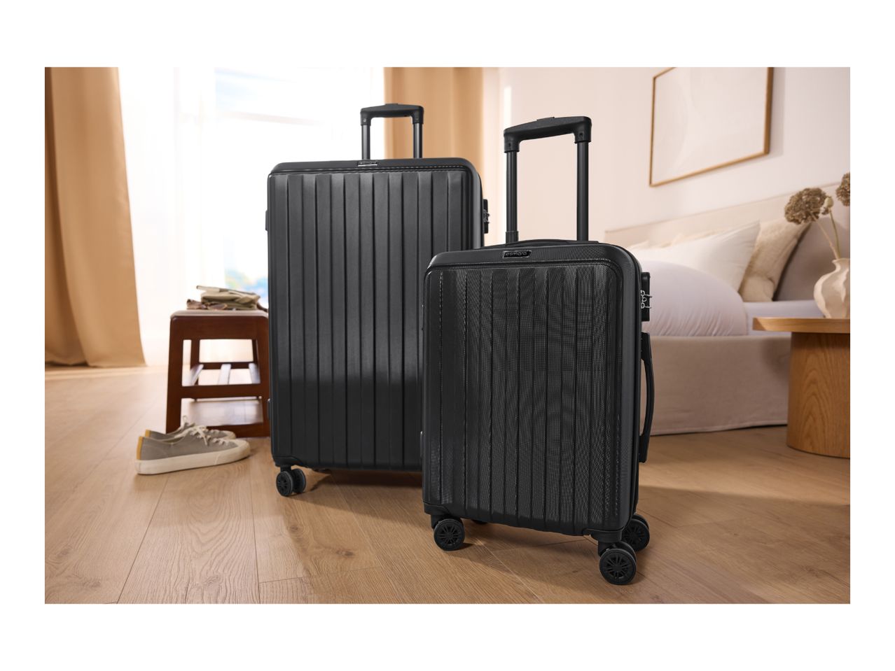 Two black suitcases, one large and one small, in a bedroom setting.