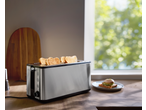 SILVERCREST Doppellangschlitz-Toaster mit Toast, neben einem Fenster mit grünem Laub.