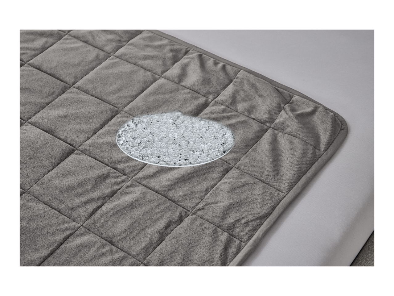 A gray quilted weighted blanket with a magnified view of the glass beads inside.
