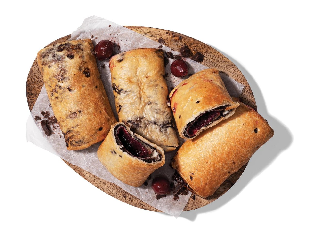 Cseresznye és csokoládés sütemények fa tálcán.