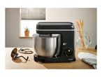 A black SilverCrest stand mixer with a stainless steel bowl on a wooden counter.