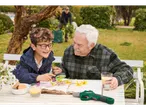 A boy and a man examine flowers in a book, with a Parkside tool on the table.