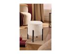 Cream boucle ottoman with black legs, next to a matching armchair and books with a drink.