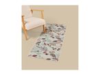 A beige armchair next to a runner rug with a fall-themed leaf and acorn pattern.