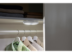 Ein kleines LED-Licht beleuchtet einen Kleiderschrank mit hängenden Kleidern.