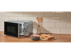 Micro-ondas SILVERCREST® 700W com tigela de sopa fumegante e pão numa bancada de madeira.