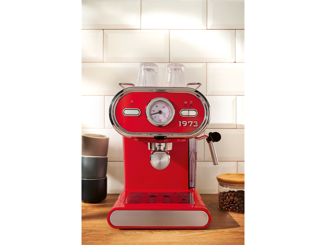 SILVERCREST® Espresso Machine in red on a wooden counter with cups and coffee beans.