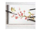A watercolor painting of birds and cherry blossoms on a spiral-bound sketchbook with art supplies.