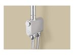 Close-up of a chrome shower mixer with two control knobs and flexible hoses against a beige wall.