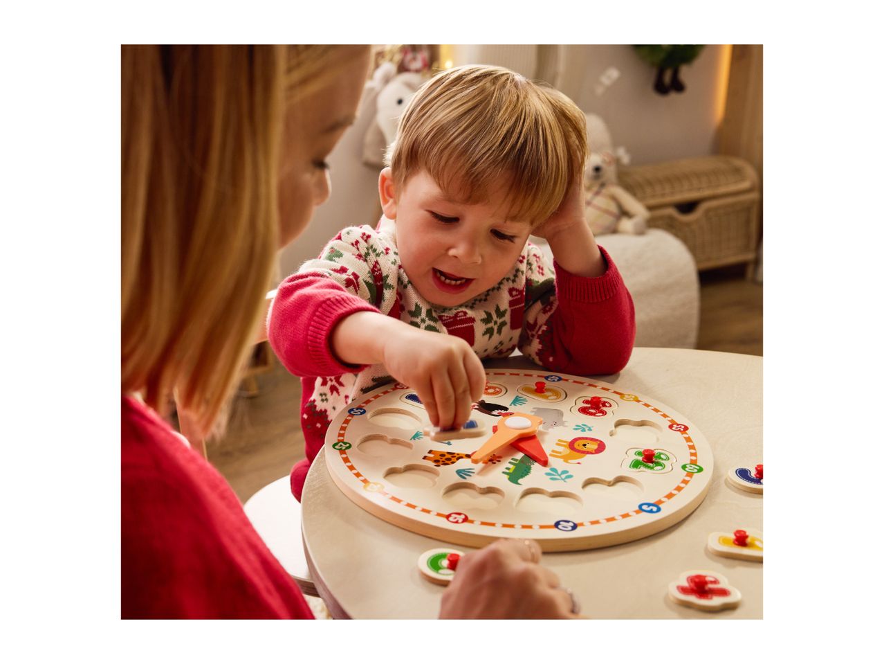 A child and adult playing with a wooden clock puzzle featuring animal shapes and numbers.