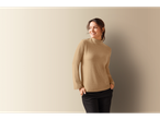 Smiling woman wearing a beige Esmara turtleneck and black pants.
