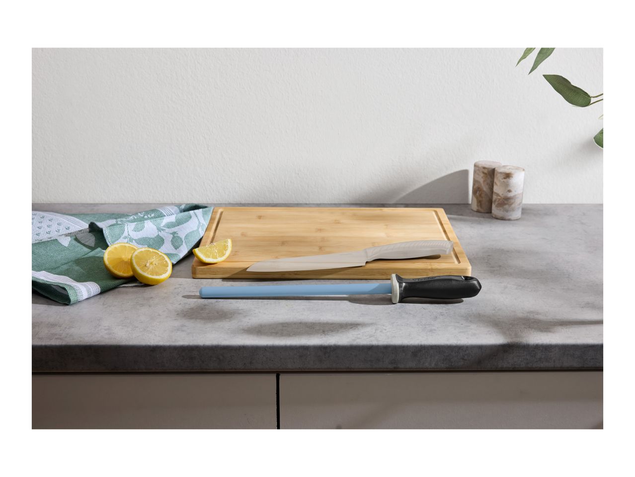 A blue ceramic sharpening rod on a kitchen counter next to a cutting board and lemons.