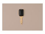 A wooden paddle brush with black bristles on a light brown background.