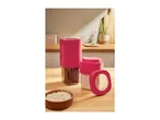 Two pink-lidded kitchen storage containers, one with beans and one with flour, on a wooden counter.