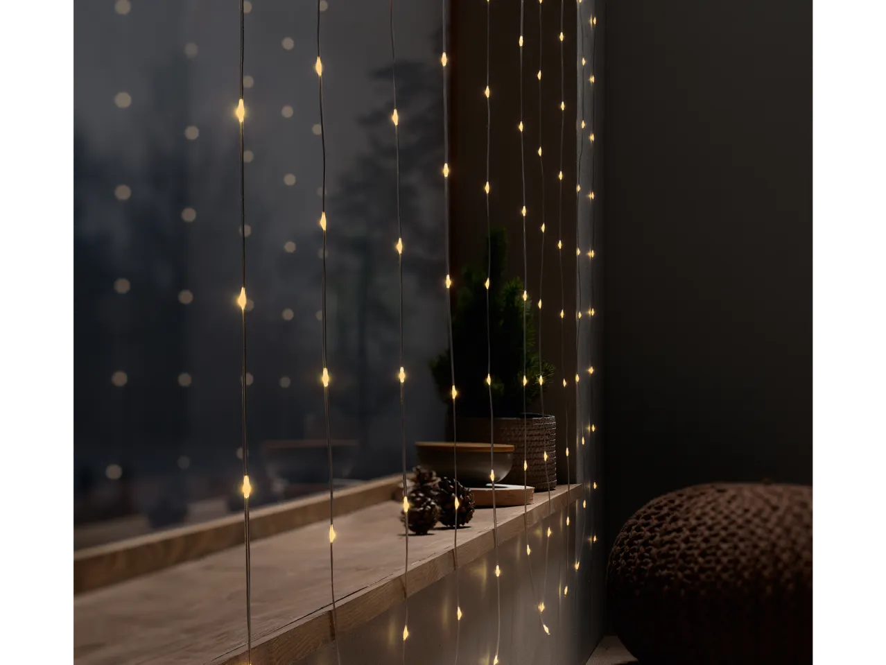 Livarno Home LED valguskardin valgustab akent käbide ja taimedega.