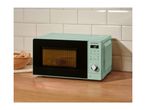 Mint green microwave oven on a wooden countertop with white tiled backsplash.