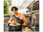 Un homme ouvre un plat à four Campingaz pour révéler un gâteau cuit au four.