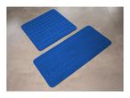 Two blue bath mats with a wavy pattern and drainage holes on a tiled floor.