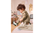 A toddler in a green bear-print outfit and animal-themed shoes plays on the floor.