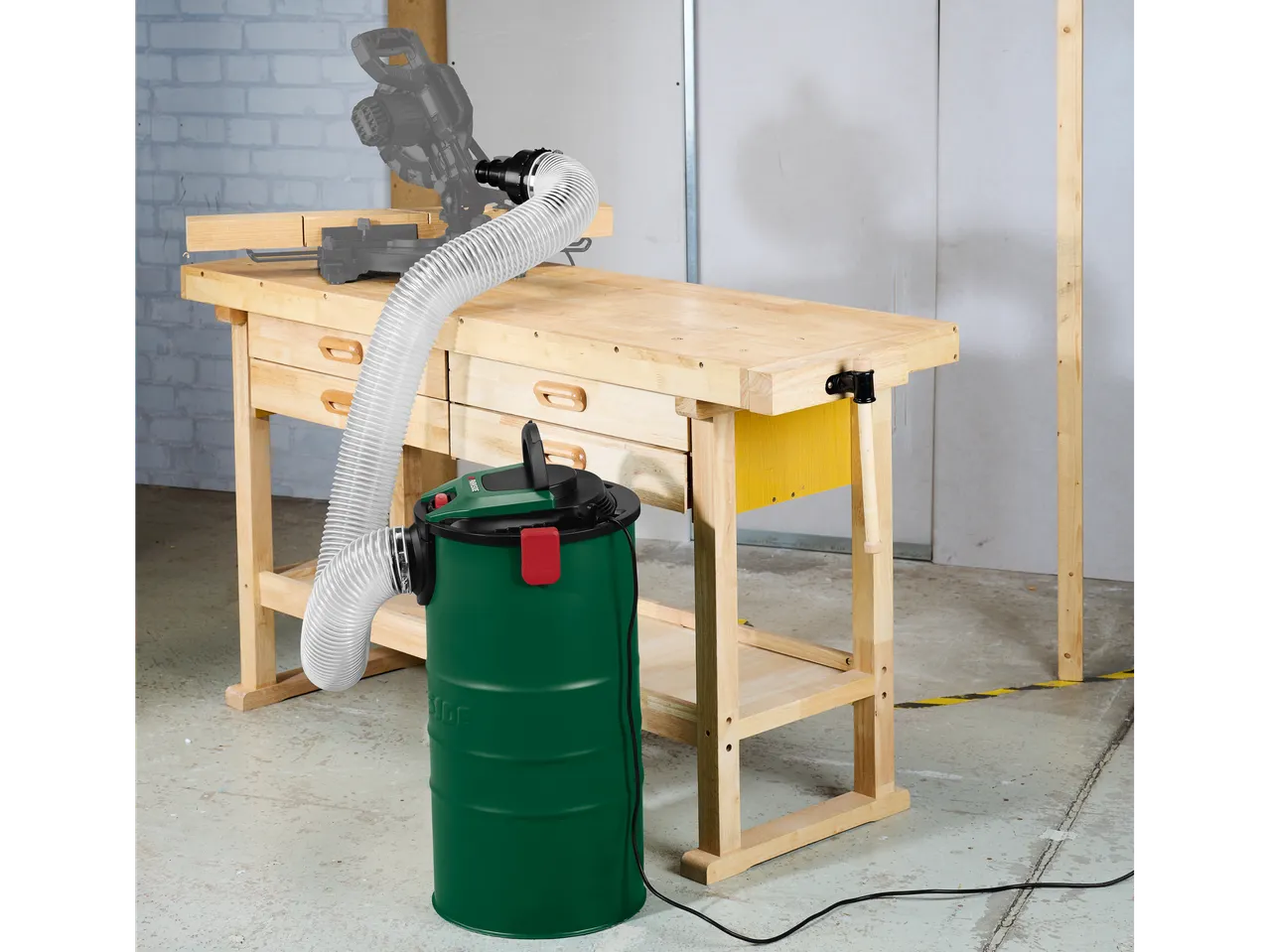 Eine Schreinerei mit einem Holzwerktisch, einer Gehrungssäge und einem Einhell-Staubsauger.