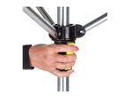 A hand holding the bright yellow handle of a silver-colored clothes drying rack.