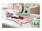 A kitchen counter with baking ingredients, a stand mixer, and a decorated cake.