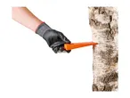 A gloved hand inserting an orange felling wedge into a birch tree trunk.