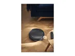 Robotic vacuum cleaner on a wooden floor next to a sofa and side table.