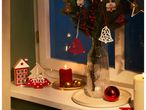 Christmas decorations on a windowsill with candles and a vase of fir branches