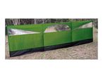 Green windbreak with clear panels, set up outdoors on grass.