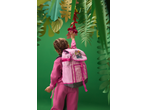 Criança de fato de treino rosa com mochila rosa, a esticar-se para decorações florais.