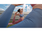 Woman in CRIVIT activewear doing yoga on a mat, sky in the background.