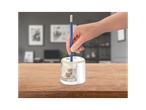 A hand inserts a blue pencil into a white and clear electric pencil sharpener on a wooden table.