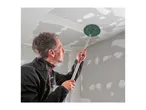Man sanding a ceiling with a long-handled drywall sander.