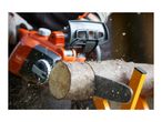 Close-up of a person cutting a log with an orange chainsaw, sawdust flying.