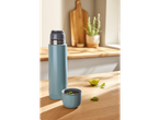 A light blue thermos and a cup with mint tea on a wooden kitchen counter.