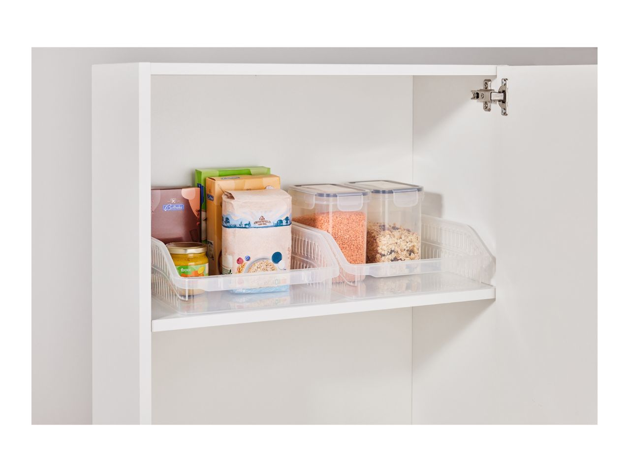 Kitchen cupboard with clear storage bins holding lentils, muesli, flour, and other groceries.