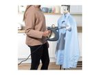 Woman steaming a light blue shirt with a handheld garment steamer.