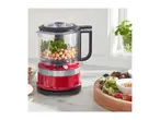 Red food processor with chickpeas and parsley, next to a salad platter.