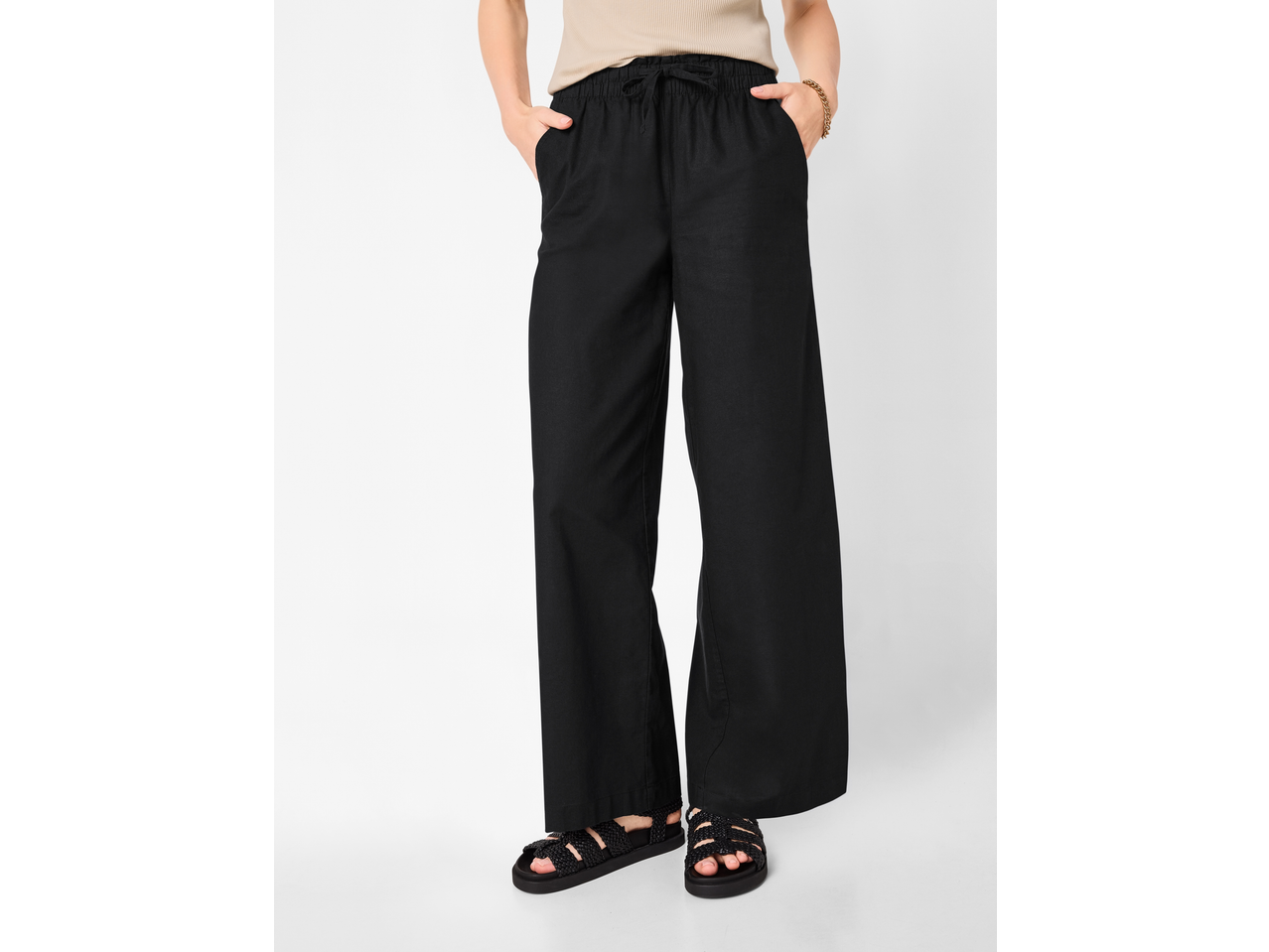 Zwarte wide-leg damesbroek met trekkoord, gestyled met een beige top en gevlochten sandalen.