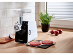 Silvercrest® electric meat grinder with raw burger patties and red onions on a kitchen counter.