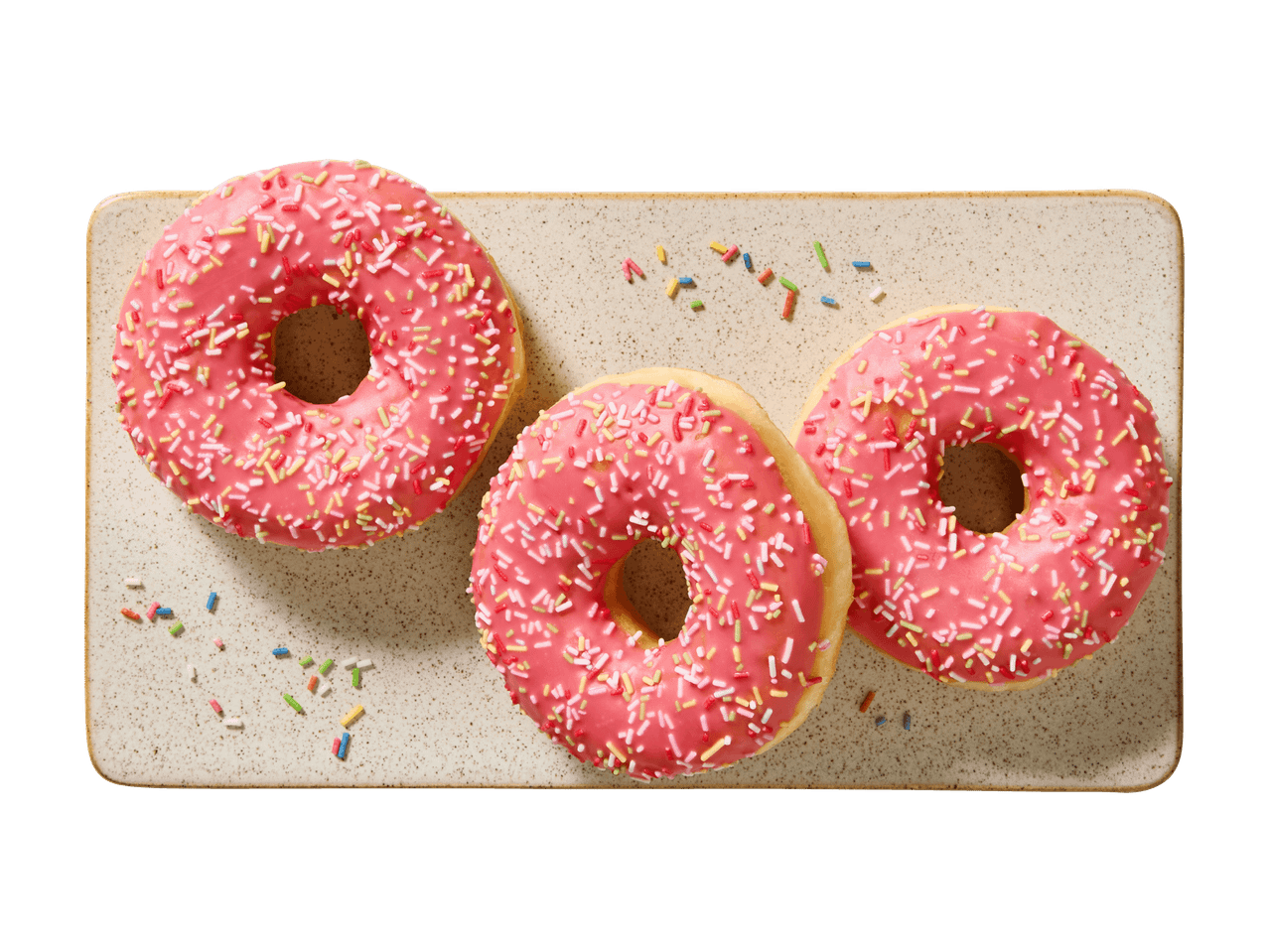 Kolme vaaleanpunaista donitsia, joissa on värikkäitä nonparelleja, suorakaiteen muotoisella lautasella.