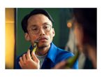 Man trimming his mustache with a Philips OneBlade electric shaver in front of a mirror.